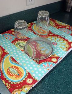 a place mat with two glass dishes on it and a cat sitting in the background