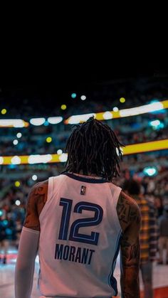 a basketball player with dreadlocks standing in front of an arena filled with people