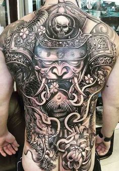 the back of a man's body with tattoos on it and an elaborate design