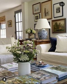 a living room filled with white furniture and lots of pictures on the wall above it