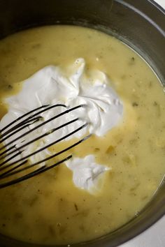 a whisk is in a pot filled with cream