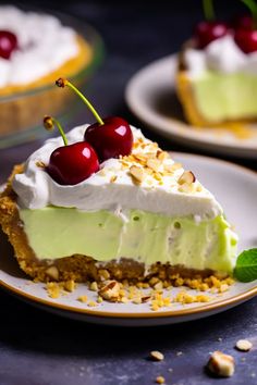 a slice of pie with cherries and whipped cream on top is sitting on a plate