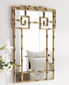 a mirror that is on the wall next to a vase with white flowers in it