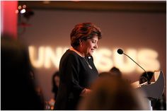 a woman standing at a podium in front of a microphone with the words unisscuss on it