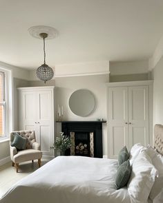 a bedroom with a bed, chair, fireplace and mirror in it's corner