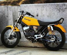 a yellow motorcycle parked next to a cement wall