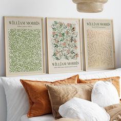 three framed art prints hang on the wall above a bed with pillows and throw pillows