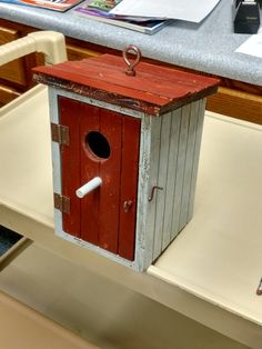 a red and white bird house sitting on top of a counter