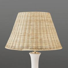 a white table lamp with a wicker shade