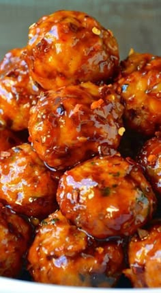 a white bowl filled with meatballs covered in bbq sauce and garnished with sesame seeds