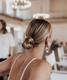 a woman sitting at a table with her back turned to the camera and wearing earrings