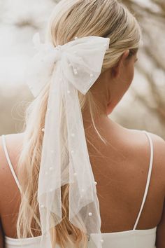 the back of a woman's head wearing a white bow with pearls on it