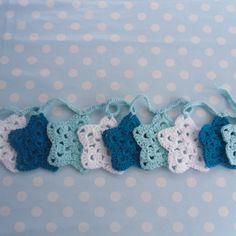 crocheted blue and white stars are hanging from a string on a polka dot tablecloth