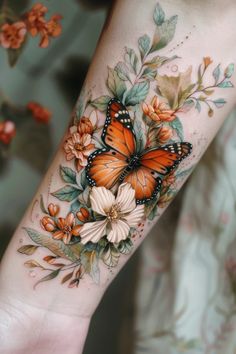 a woman's arm with an orange butterfly and flowers on it