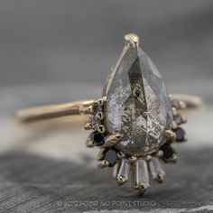 a close up of a ring with a stone and black stones on the side,