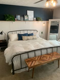 a bed sitting in a bedroom next to a wooden table and lamp on top of it