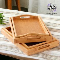 two wooden trays sitting on top of a bed next to each other with handles