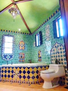 a bathroom with green and yellow tiles on the walls