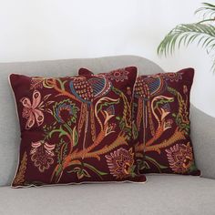 two pillows sitting on top of a couch next to a plant