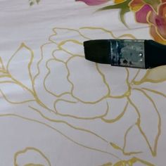 a close up of a black object on a white table cloth with flowers in the background