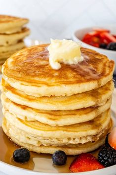 a stack of pancakes with butter and berries on the side