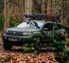 a green pick up truck parked in the woods with its roof rack mounted on it