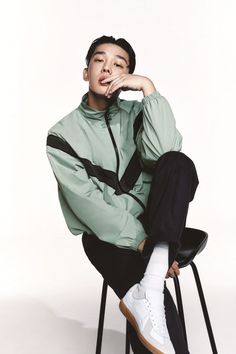 a young man sitting on top of a chair with his chin resting on his hand