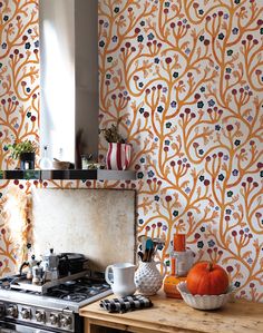 an orange and white wallpaper in a kitchen with stove top oven, cabinets and counter tops