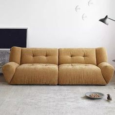 a brown couch sitting on top of a white floor next to a table and lamp