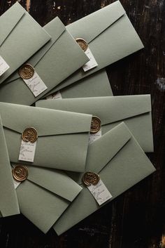 several green envelopes with waxed seals on them and some gold foil stamping