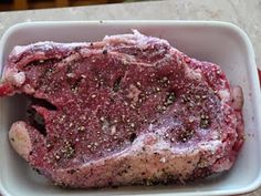 a piece of raw meat sitting in a white bowl on top of a marble counter