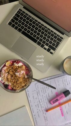 an open laptop computer sitting on top of a desk next to a bowl of food