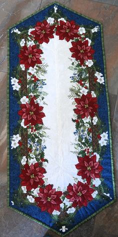 a christmas table runner with poinsettis and holly