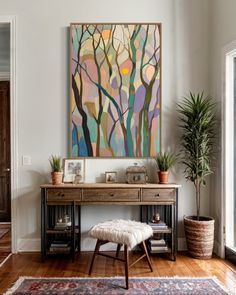 a painting hanging on the wall next to a desk with a stool and potted plant