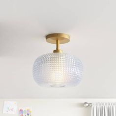 a ceiling light with a glass ball shade hanging from it's center point in a bedroom