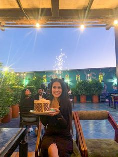 a woman sitting at a table holding a cake