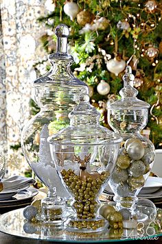 a christmas tree is in the background behind glass jars with ornaments on top and below