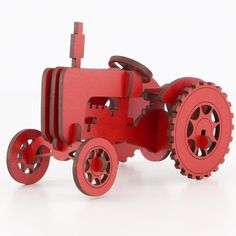 a red wooden toy tractor with wheels on a white background