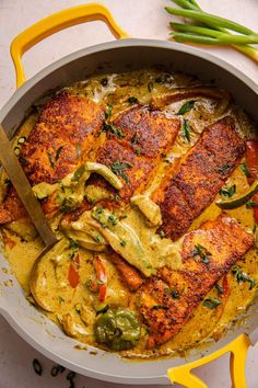 a pan filled with chicken and vegetables on top of a white countertop next to green beans