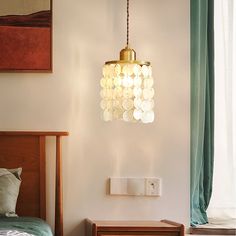 a lamp hanging over a bed next to a window