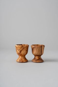 two wooden bowls sitting side by side on a gray surface, one is made out of wood