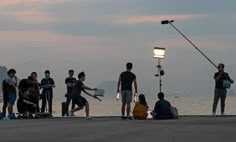 a group of people standing next to each other near the ocean with a light on