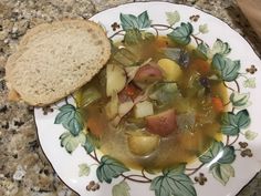 a white plate topped with soup next to a piece of bread