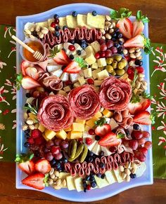 a platter filled with fruit, cheese and meats on top of a table