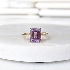 a pink tourmaline ring sitting on top of a white surface