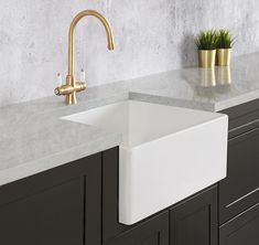 a white sink sitting on top of a counter next to a potted green plant