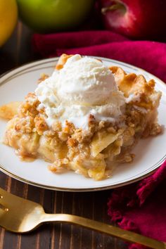 a piece of pie on a plate with ice cream and apples in the back ground