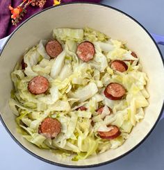 a pan filled with cabbage and sausage on top of a table