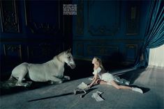 a woman sitting on the floor next to a white horse