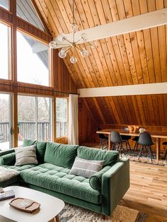 a green couch sitting in the middle of a living room next to a wooden ceiling